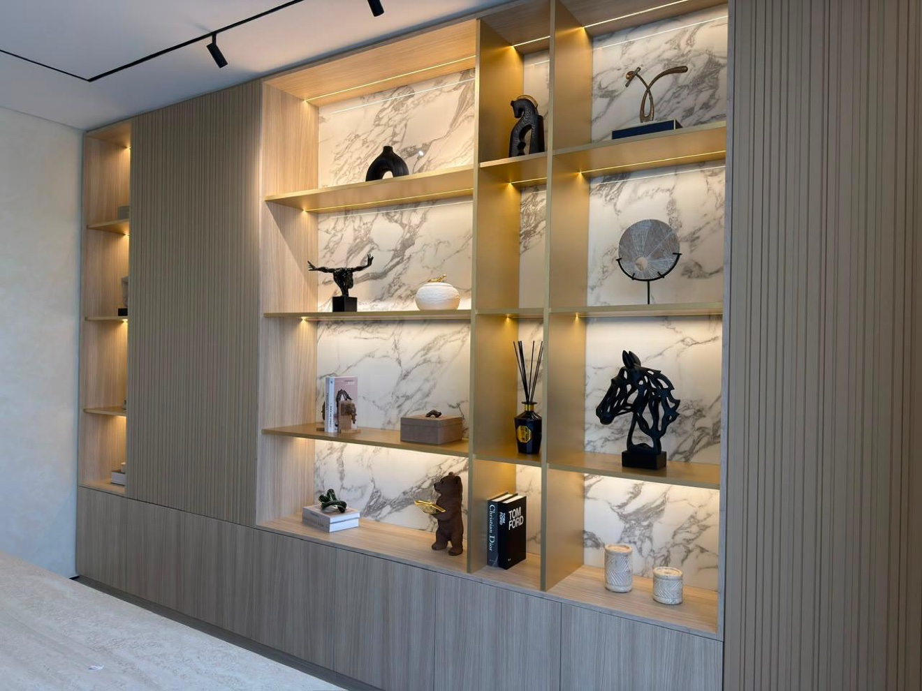 Full-height display shelving wall with concealed lighting and curated ceramics