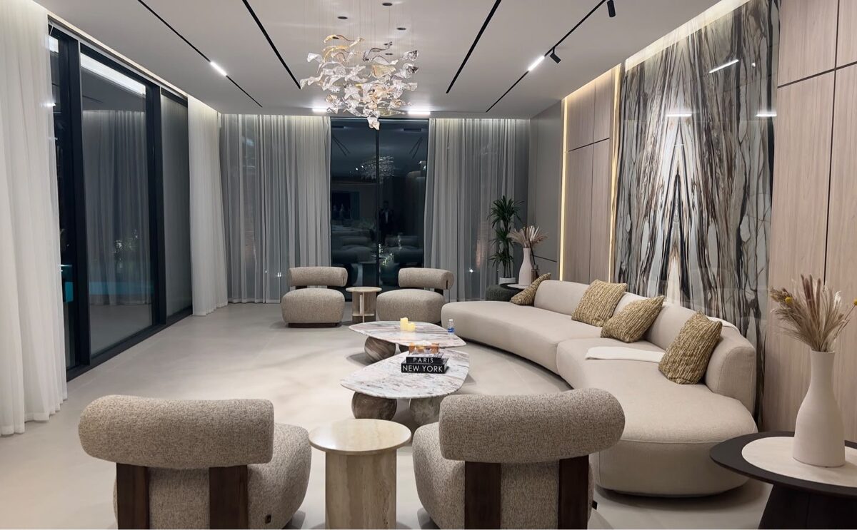 Formal living room of Wild Flower villa, Jumeirah Golf Estates — book-matched stone feature wall, curved sofa and glass-leaf chandelier