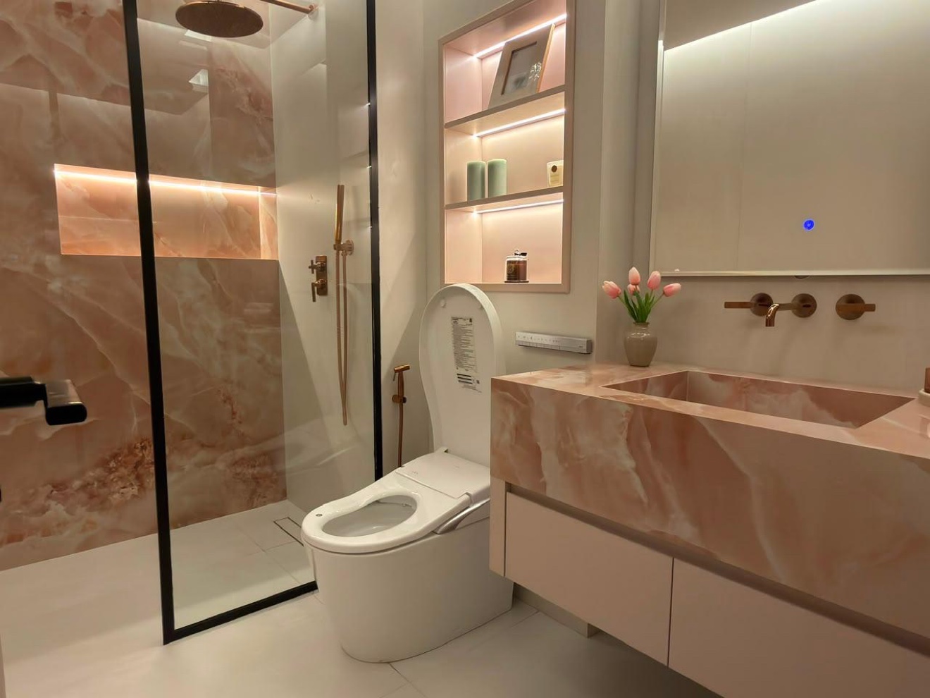 Bathroom in book-matched rose stone with double marble vanity and brass fittings