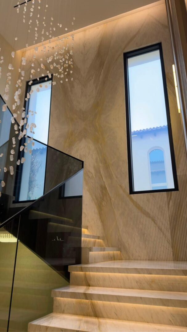 Marble staircase with illuminated steps, fluted stone wall and crystal pendants