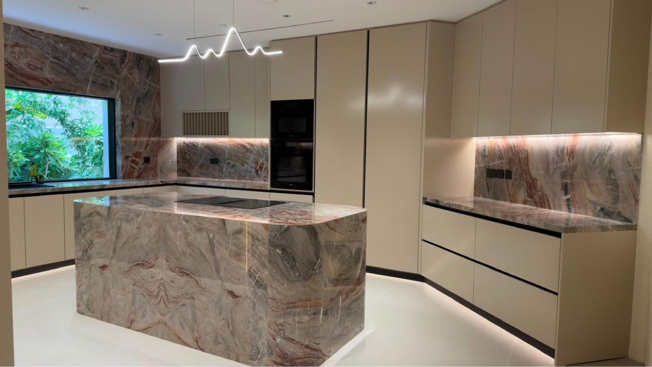 Kitchen island in book-matched stone with sculptural pendant light and integrated appliances