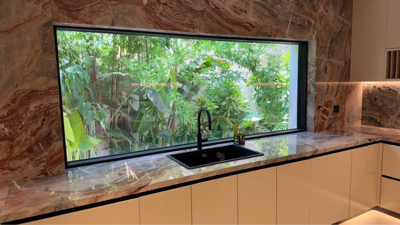 Kitchen worktop and sink beneath a full-height garden window with matte black fittings