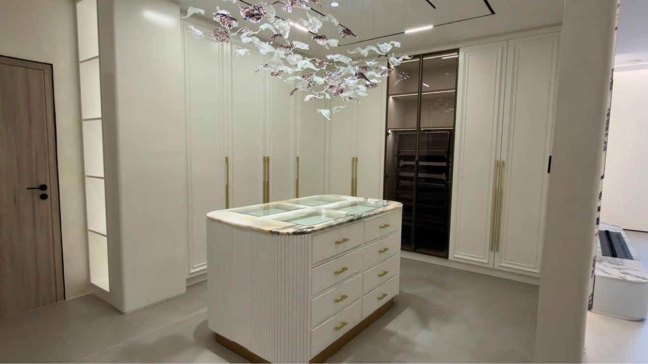 Dressing room with central island dresser, glass wardrobes and leaf chandelier