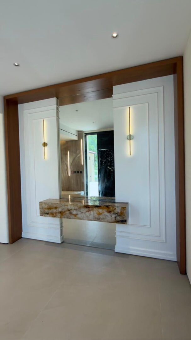 Powder room with book-matched stone walls and illuminated round mirror