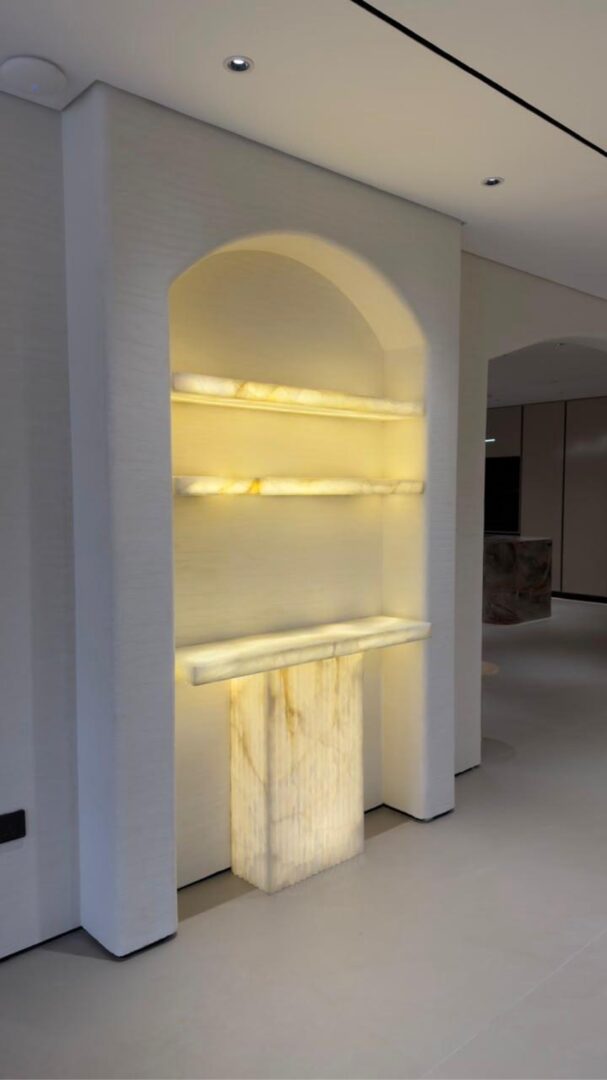 Arched niche with backlit onyx shelving and marble pedestal